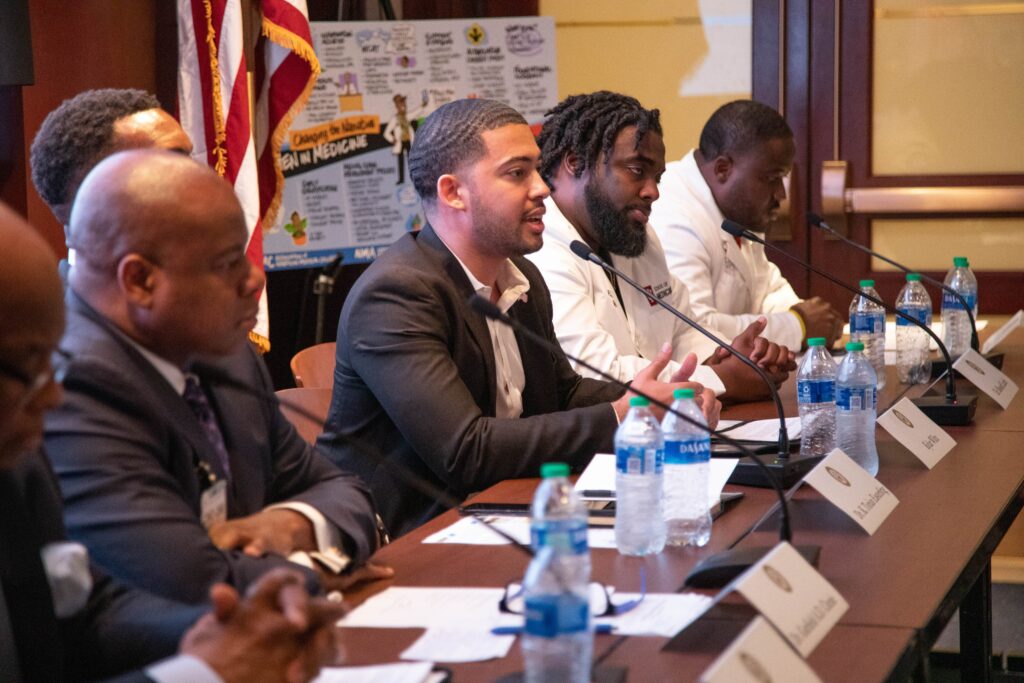 Kylar Wiltz speaks into a microphone during a Congressional Briefing for Black Men and Boys in Medicine